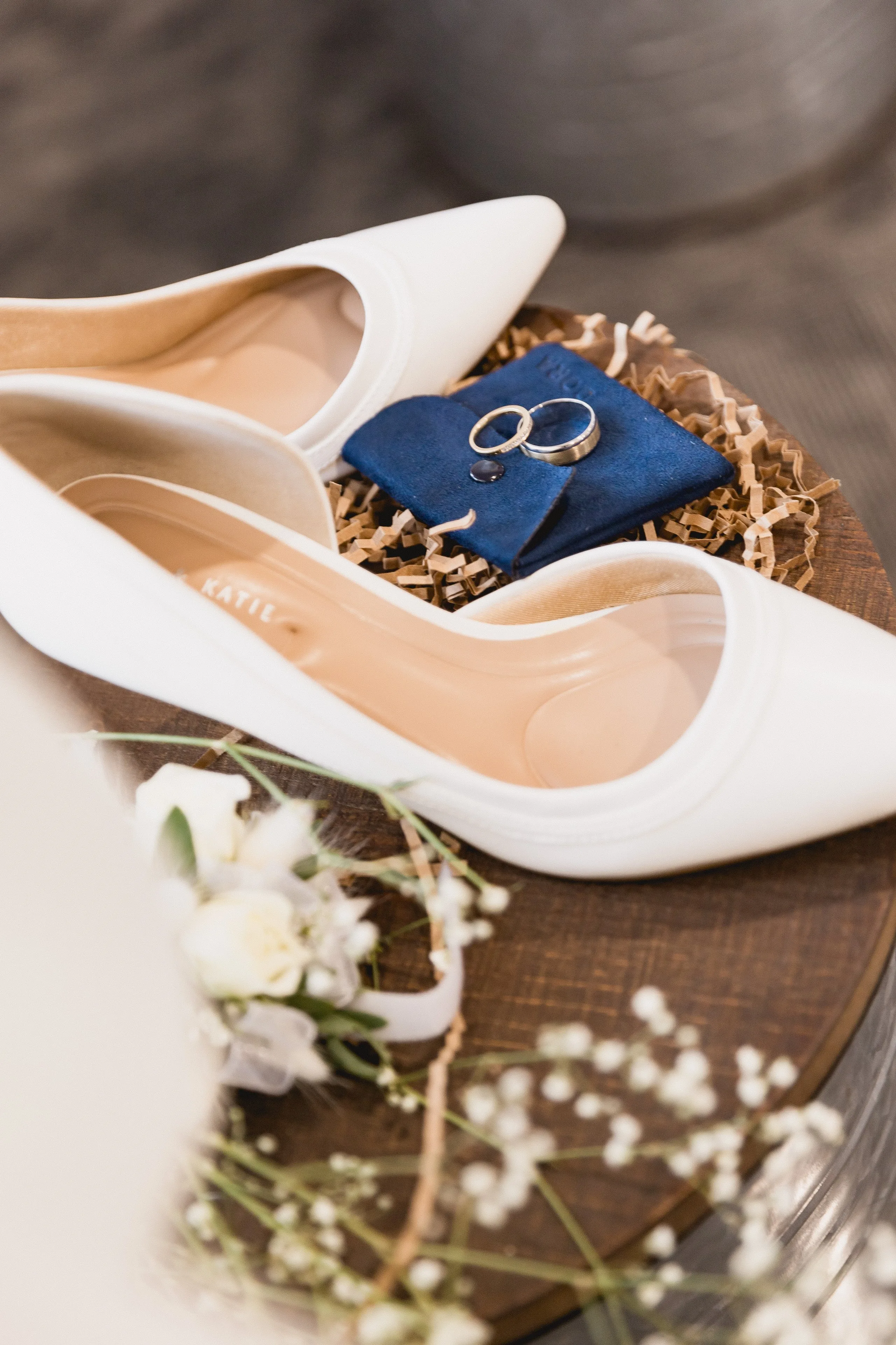 Bridal shoes and wedding rings on a navy velvet pouch, detail still life