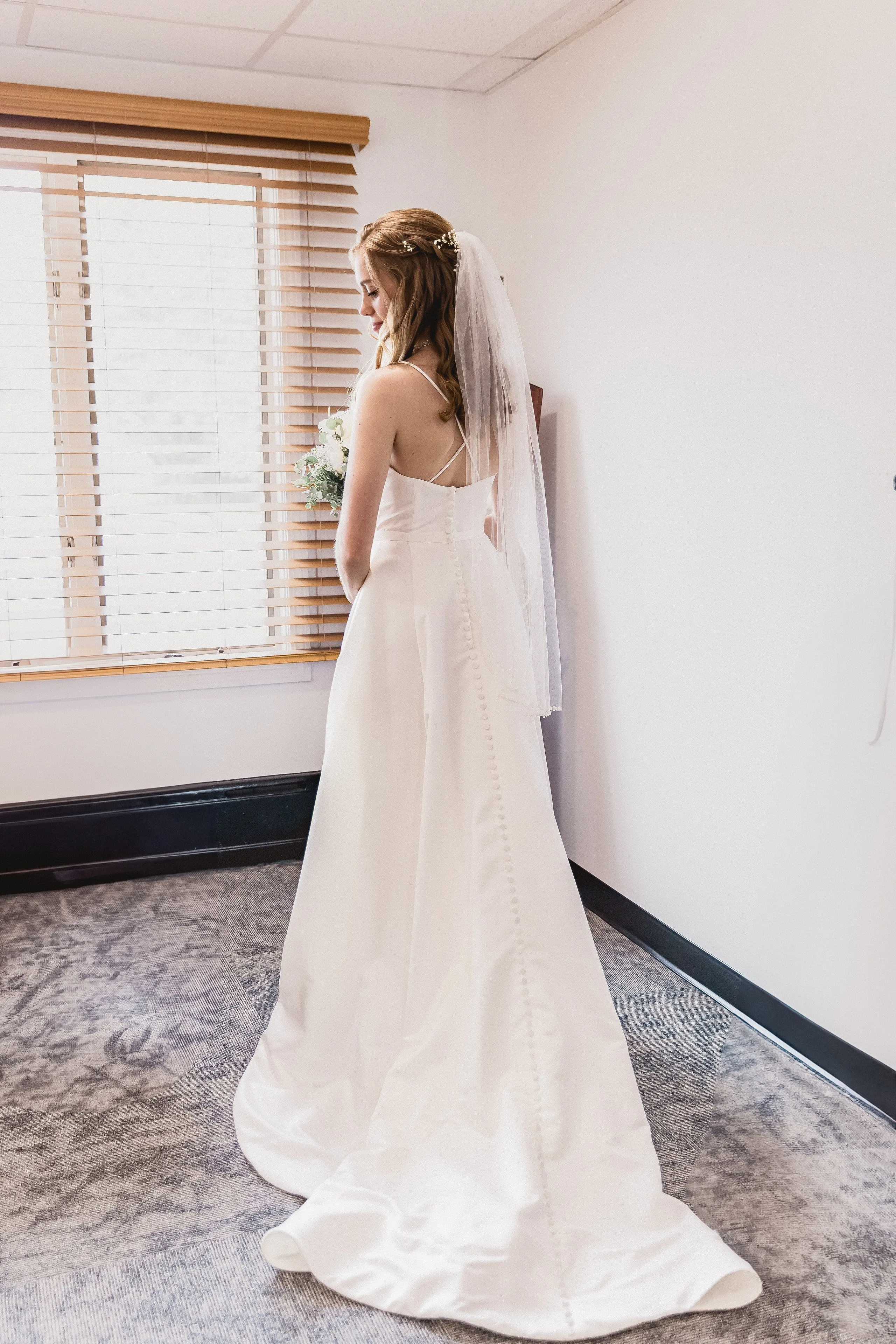 Bride in window light with veil trailing, photographed by Sharon of Nissi Photo