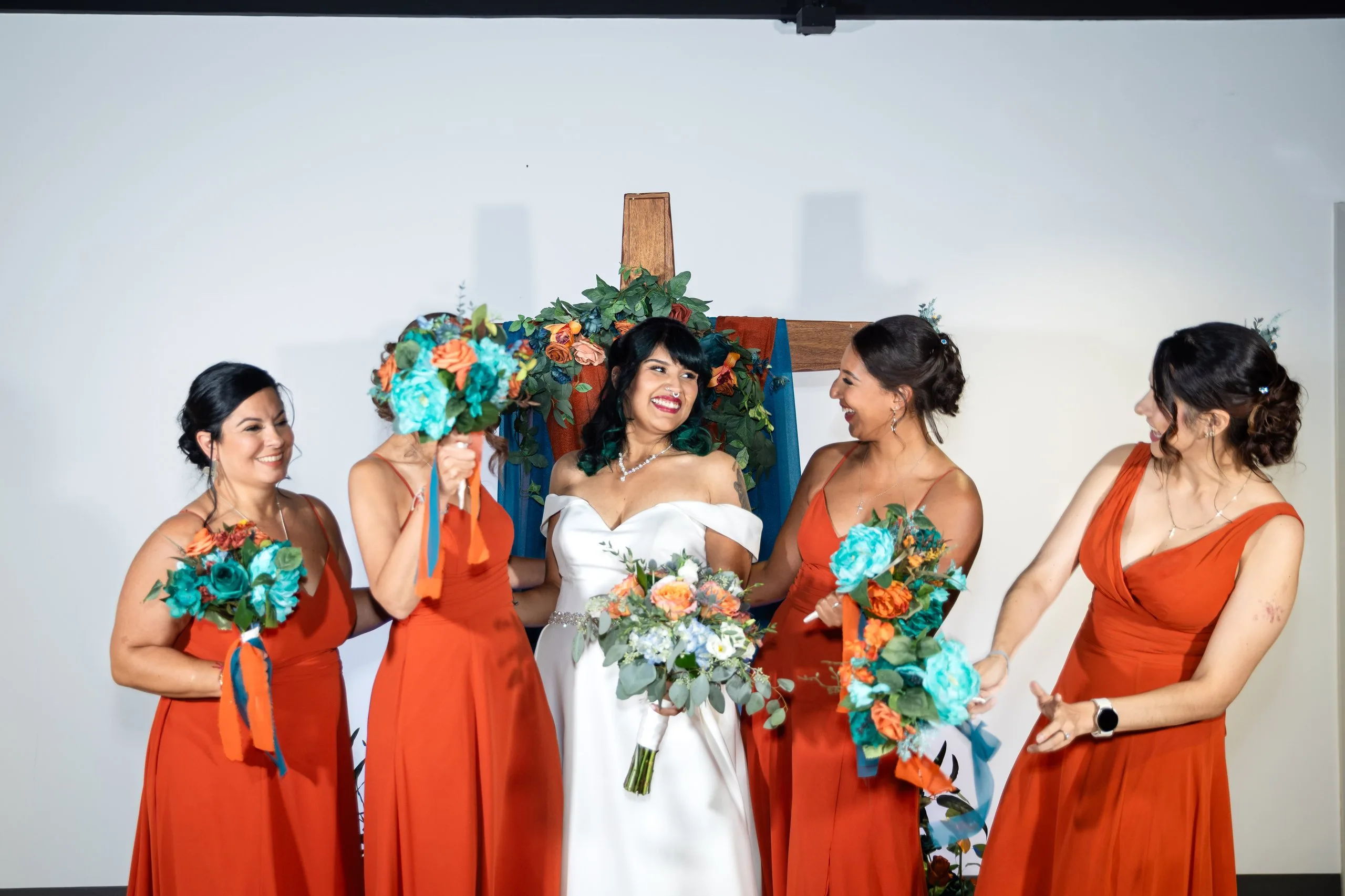 Bride laughing with bridesmaids in terracotta dresses